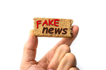 Fake news sign on a piece of wood between fingersの写真素材