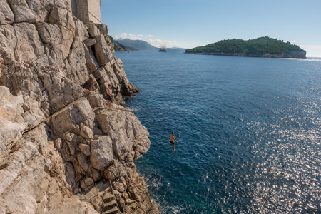 Man Jumping Off the Rocks Into sea.の写真素材