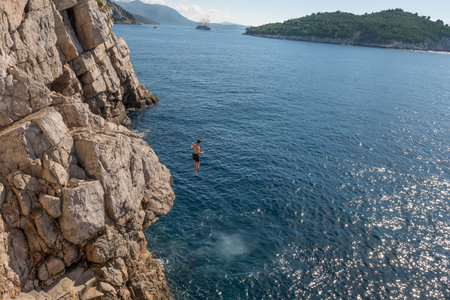 Man Jumping Off the Rocks Into sea.の写真素材