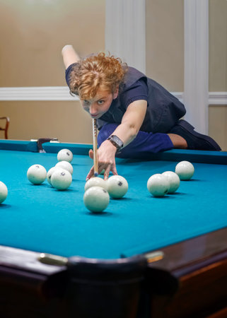 Curly-haired girl plays Billiards, performs a difficult blow. Curly-haired girl plays Billiards,...