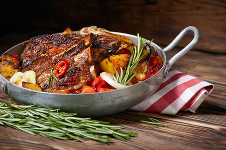 Fried ribs in a pan with rosemary, potatoes rustic, onion, sauce . Dark background.の写真素材