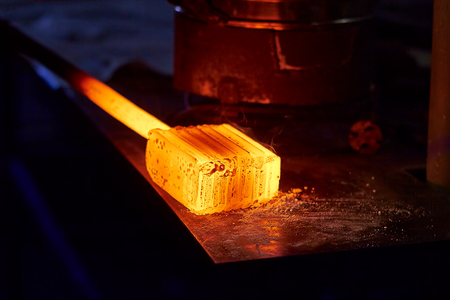 Glowing iron ingot on the table. Hot metal workpiece for the manufacture of Damascus steel.の写真素材