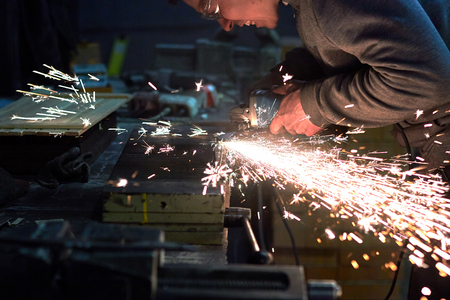 Worker Processes the iron part of the grinding machine, the sparks fly in different directionsの写真素材