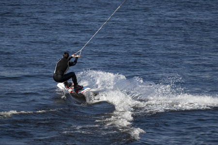 A man on a blue sea on a white spray wakeboard.の写真素材