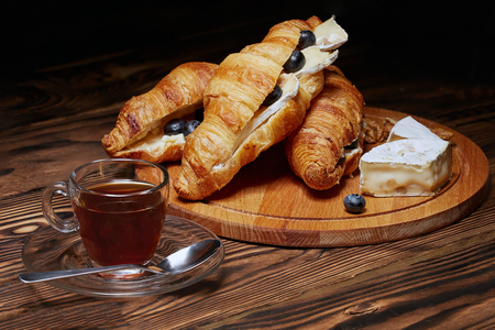 Coffee with croissant, nuts, Camembert cheese on a dark wooden background.の写真素材