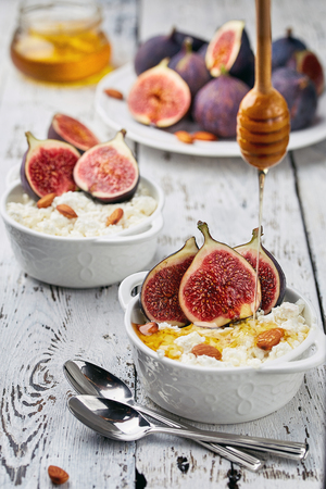 Cottage cheese with Figs, honey and almonds in a white bowl on a light background. Concept: healthy Breakfastの写真素材
