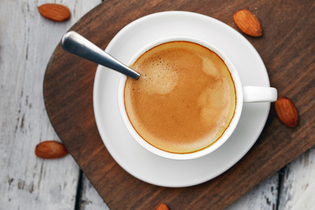 Coffee with foam and almonds on wooden background. Concept: coffee with almond taste.の写真素材