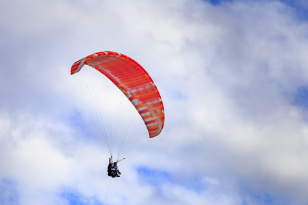 Paraglider flying against the blue sky with cloudsの写真素材