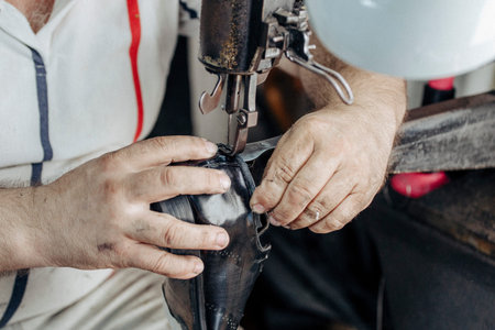 Man sews shoes on the sewing machine. Shoe repair
