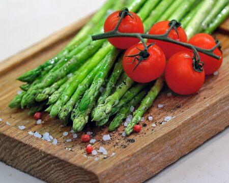 fresh vegetables asparagus and tomatoes on wooden boargの写真素材