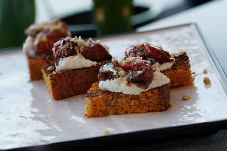 Bruschetta, toasted slices of bread with feta cheese, dried tomatoes, on a white plate.の写真素材