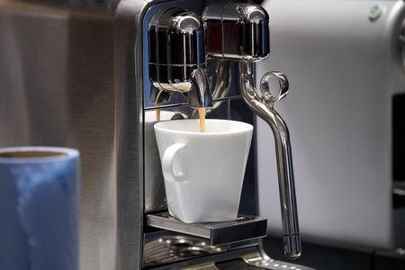chrom coffee machine making and pouring in white cup. capsule coffee machinの写真素材