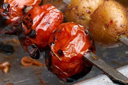Vegetables on skewers on the grill, vegetarian shish kebab from potatoes and tomatoesの写真素材
