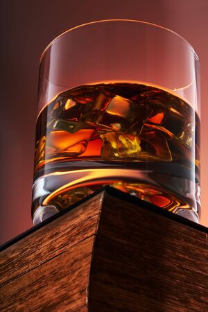 glass of whiskey with ice on an old book. bottom view. close upの写真素材