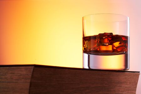 glass of whiskey with ice on a wooden table. space for notesの写真素材