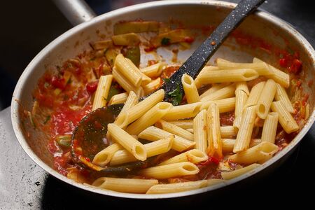cooking food of italian cuisine, pasta with tomato sauce, detailed view of spoon and pan fryingの写真素材