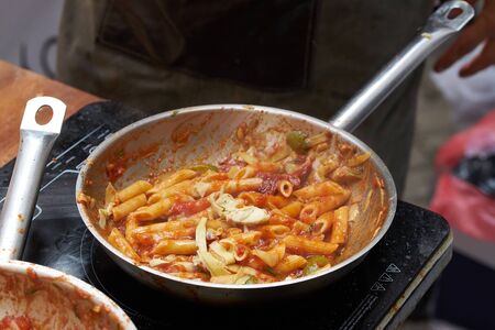 cooking food of italian cuisine, pasta Penne with tomato sauce, detailed view of spoon and pan fryingの写真素材