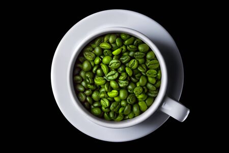 Coffee cup with raw beans on black background. green coffee beans. Top view. isolateの写真素材