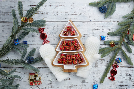 lots of little red gift boxes in the shape of a Christmas tree on a white wooden background. White...