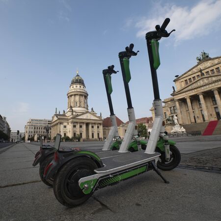 electric scooters are parked at the Gendarmenmarkt in Berlin. a number of e-scooters on the background of the Berlin drama theatre. sunny summer dayの写真素材