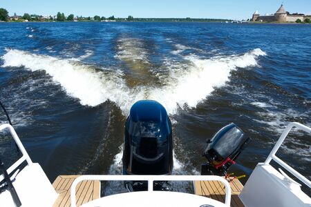 Boat in motion with of powerful engines at the stern and foam wake behind the stern of fast moving motor boatの写真素材