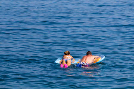 man and a woman on an air mattress floating on the seaのeditorial素材
