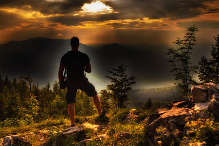 A man at the top of the mountain during the sunset