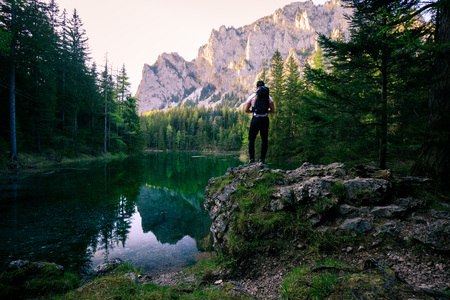 Beautiful green lake in austria with a hiker standing on a rockの写真素材