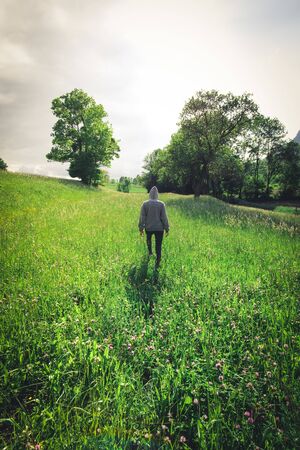 Young woman in summer field. View from the back in austriaの写真素材