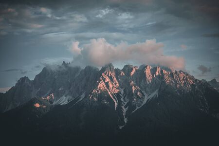 Mountains in morning sunrise light with sun flare in the dolomites italy during summerの写真素材