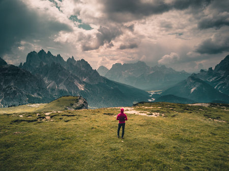 young man enjoying the view of the mountains landscape in the dolomites mountain range. tre cime di...