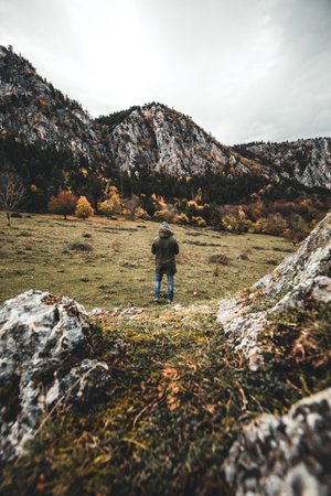 man is standing near a forest in the mountains during autumn in austria