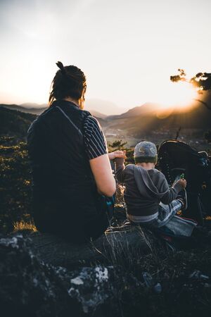 woman with child together outdoor in summer on a mountain peak during sunset in austriaの写真素材