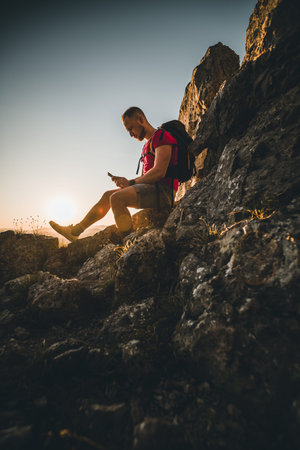 Man with mobile phone on top of mountain enjoying the sunset in the alps of austria