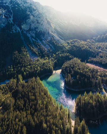 A drone shot of an Alpine valley in Austria. The valley has a Green Lake in the middle. A headland in the middle of the lake.の写真素材