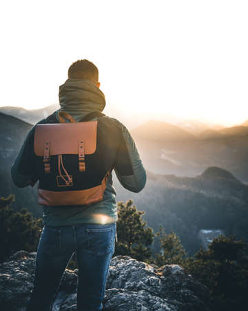 Hiker with backpack standing on top of a mountain and enjoying sunrise in the austrian alpsの写真素材