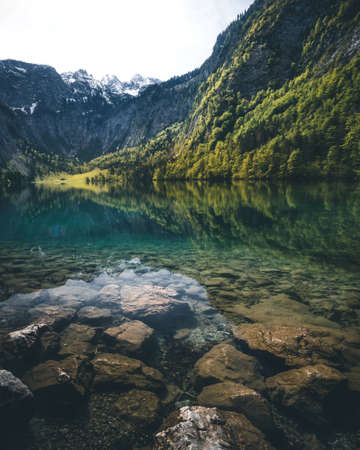 Breathtaking view of green turquoise crystal clear alpine lake Obersee Koenigssee in Bavaria, Germanyの写真素材