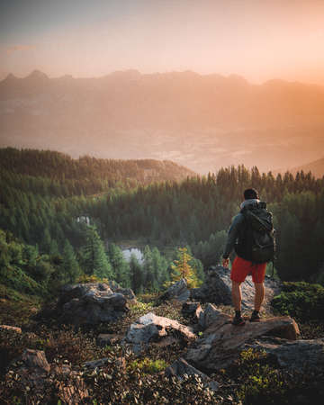 Man standing on a ledge of a mountain, enjoying the View in the Alps of Austriaの写真素材