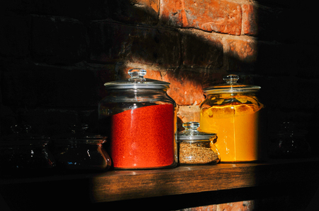 Glass jars of assorted spices and herbs  on a wooden shelfの写真素材