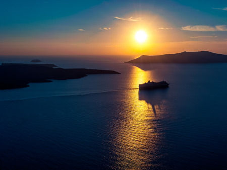 Cruise ship silhouette in sunset light with a few islands on backgroundの写真素材