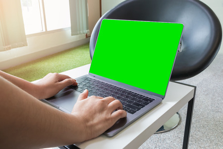 Woman typing on keyboard laptop computer and green screen with clipping path on screen for insert other objects.の写真素材