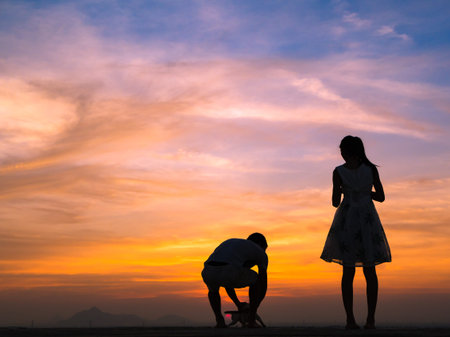 Silhouette of Happy Young Couple love Outside at Sunsetの写真素材