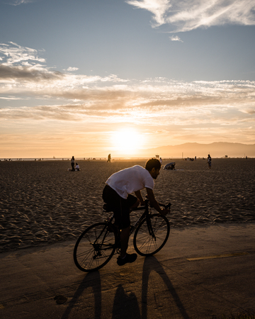 LOS ANGELES, USA - AUGUST 03 2019:  Cyclists at Venice Beach at sunset during the summer in Los Angeles USAのeditorial素材