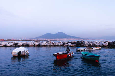 NAPLES, IT - 27 DECEMBER 2019: View of a fisherman on his boat with the Mount Vesuvius on the background at sunsetのeditorial素材