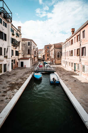 Narrow canal with boats in Venice Italyの写真素材