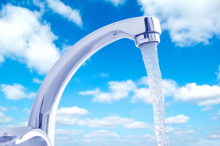 Water flowing from the faucet against the blue skyの写真素材