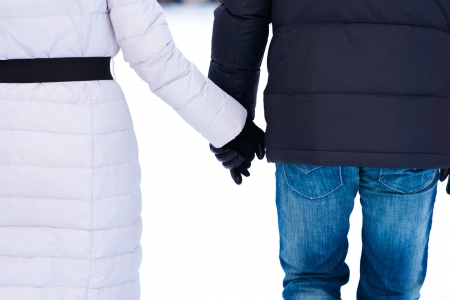Rear view of couple holding hands and walking on the bright clear snowの写真素材