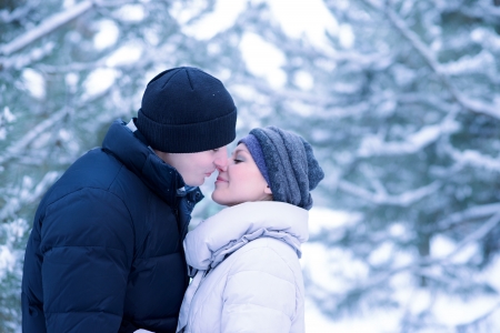 Portrait of a Young Beautiful Couple Kissing Outdoors in Snowy Winterの写真素材