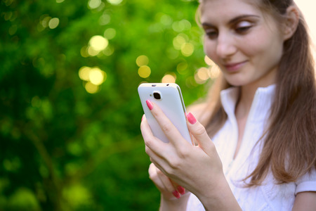 Young Beautiful Woman Using her Smart Phone Outdoorsの写真素材