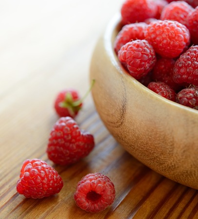 Ripe Red Juicy Raspberries in the Wooden Bowl on the Wooden Tableの写真素材